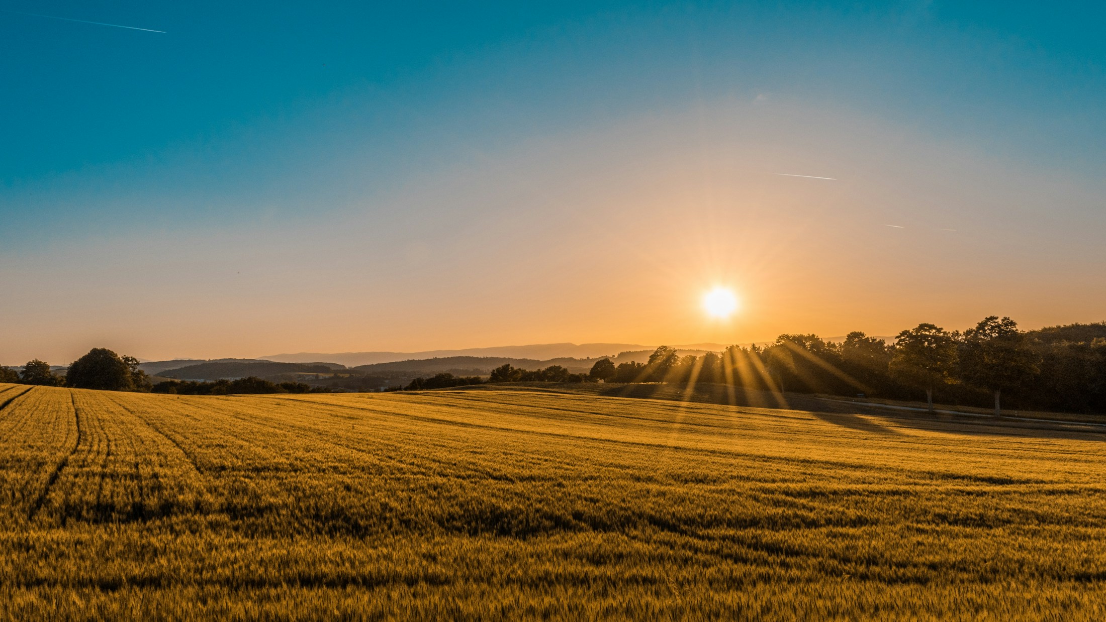 Sunlight falling across open agricultural fields and rolling green countryside